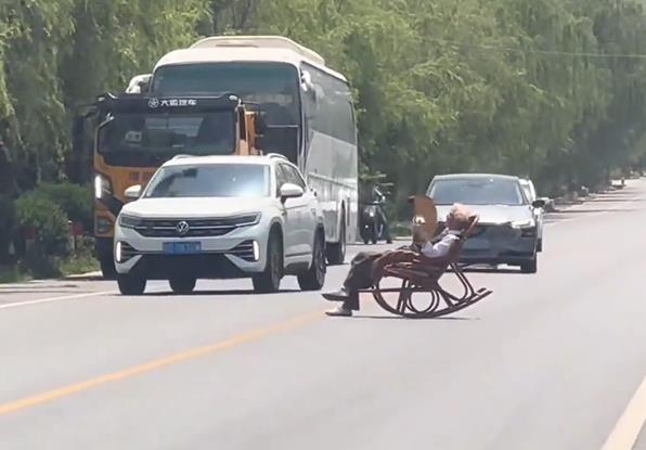 大爷躺马路中间晒太阳 车辆纷纷避让